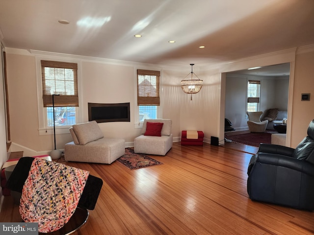 living room with an inviting chandelier, ornamental molding, and hardwood / wood-style floors