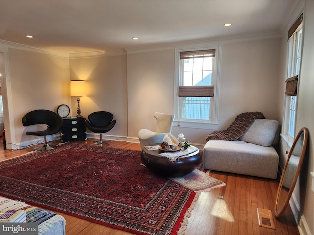 living area featuring crown molding and light hardwood / wood-style flooring