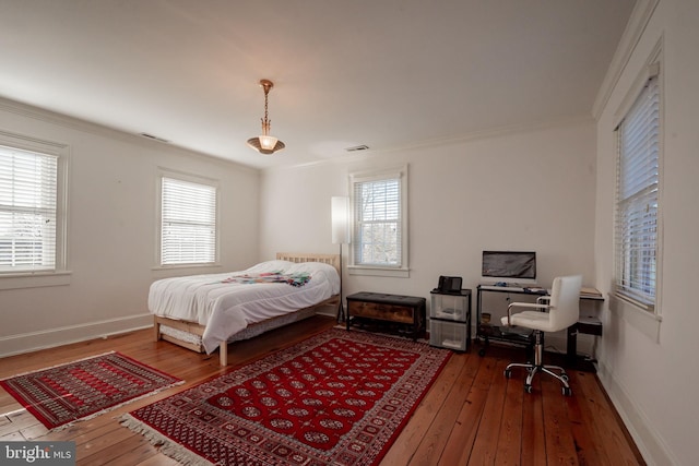 bedroom featuring multiple windows, wood-type flooring, and ornamental molding