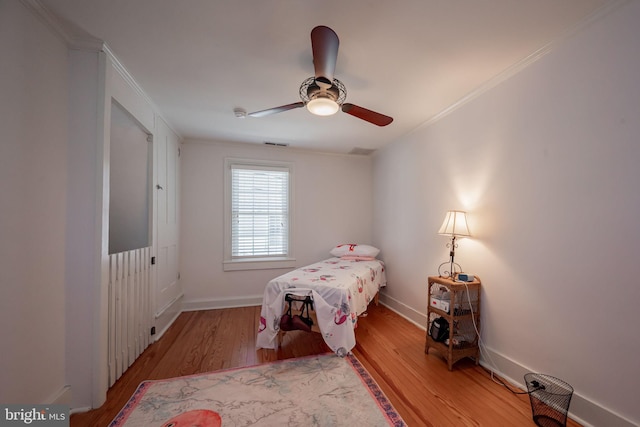 bedroom with ornamental molding, ceiling fan, and light wood-type flooring