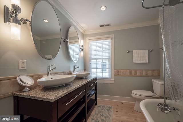 bathroom featuring ornamental molding, toilet, hardwood / wood-style flooring, and vanity with extensive cabinet space