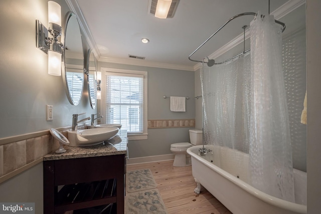 full bathroom with hardwood / wood-style floors, shower / bath combo with shower curtain, vanity with extensive cabinet space, toilet, and ornamental molding