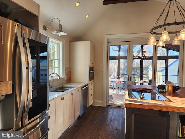 kitchen with dark wood-type flooring, white cabinetry, stainless steel appliances, a notable chandelier, and sink