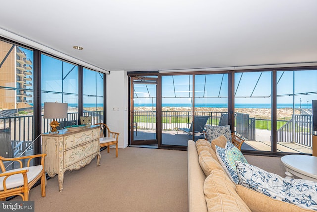 carpeted living room featuring plenty of natural light, a water view, and expansive windows