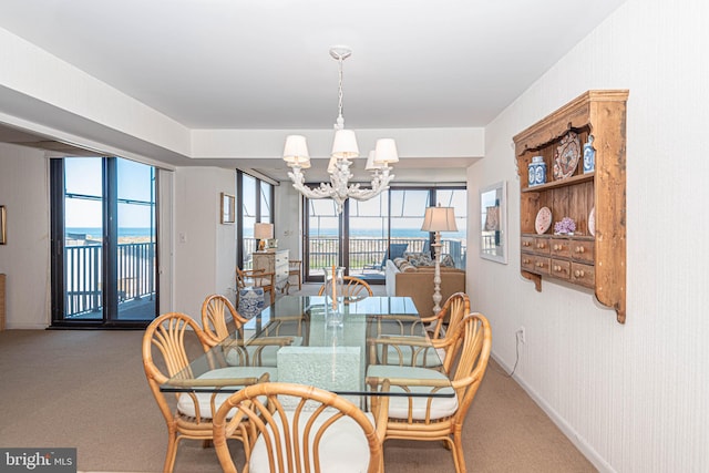 dining room featuring an inviting chandelier, a water view, and carpet flooring