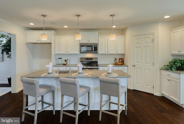 kitchen with recessed lighting, a sink, white cabinetry, appliances with stainless steel finishes, and dark wood finished floors