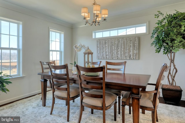 dining room featuring ornamental molding, a notable chandelier, baseboards, and wood finished floors