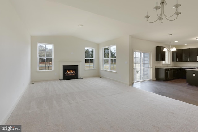 unfurnished living room featuring an inviting chandelier, light hardwood / wood-style flooring, sink, and vaulted ceiling