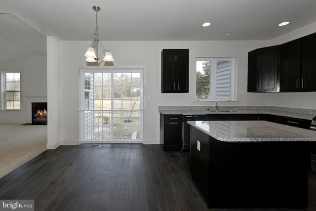 kitchen with sink, light stone counters, a chandelier, and a healthy amount of sunlight