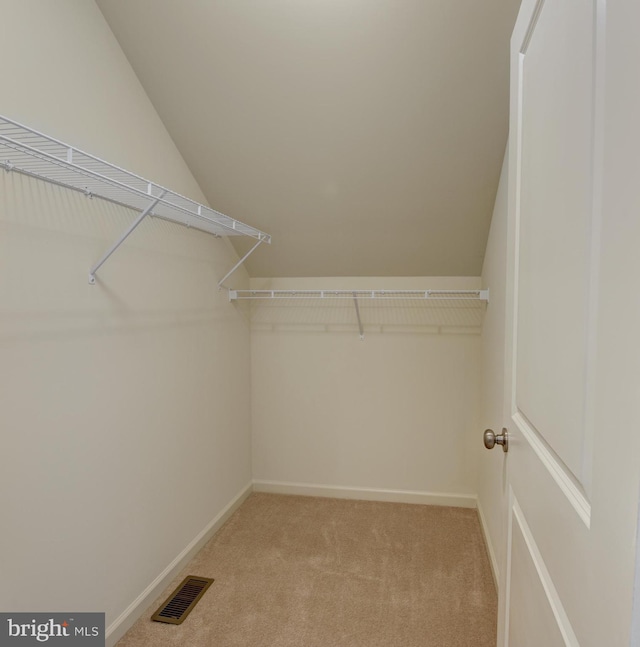 walk in closet with light carpet and lofted ceiling