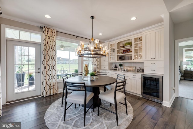 dining area featuring dark hardwood / wood-style floors, crown molding, beverage cooler, and an inviting chandelier