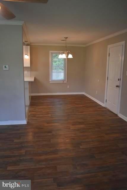 spare room with dark hardwood / wood-style flooring, ceiling fan with notable chandelier, and ornamental molding