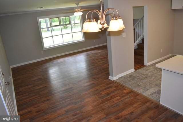 unfurnished dining area featuring dark tile floors and ceiling fan with notable chandelier