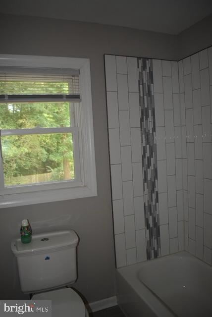 bathroom with toilet and tiled shower / bath combo