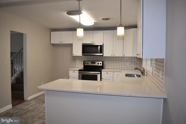 kitchen with white cabinetry, sink, stainless steel appliances, tasteful backsplash, and dark hardwood / wood-style flooring