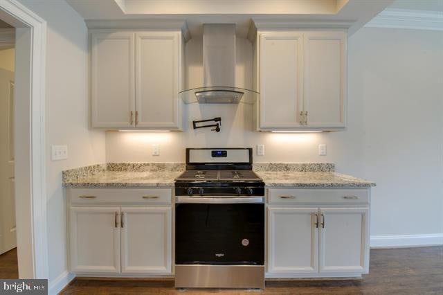 kitchen featuring stainless steel range oven, white cabinetry, dark hardwood / wood-style floors, and wall chimney range hood