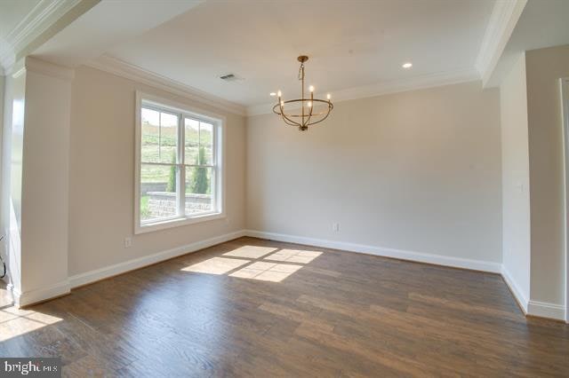 empty room featuring an inviting chandelier, dark wood-type flooring, and ornamental molding