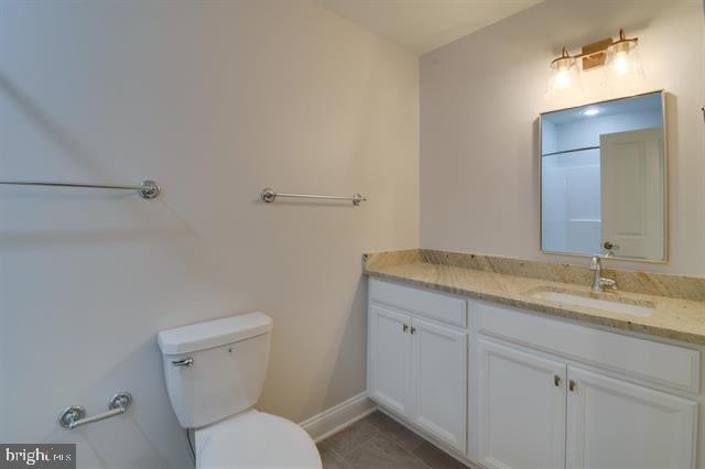 bathroom featuring toilet, vanity, and tile flooring