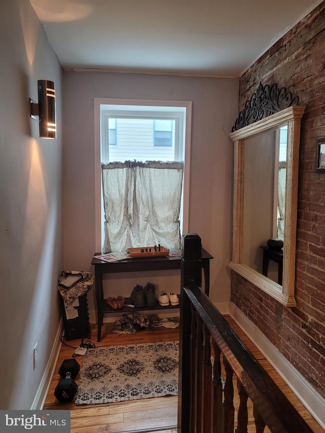 stairway with brick wall and wood-type flooring