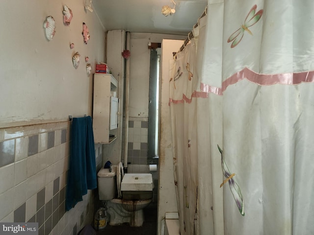 bathroom featuring tile walls, toilet, and sink