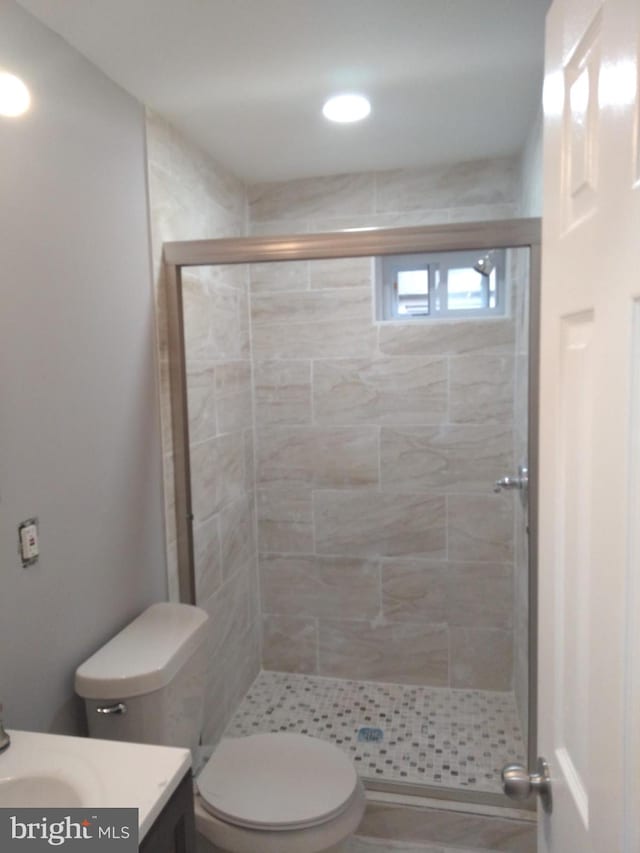 bathroom featuring vanity, a shower with door, and toilet