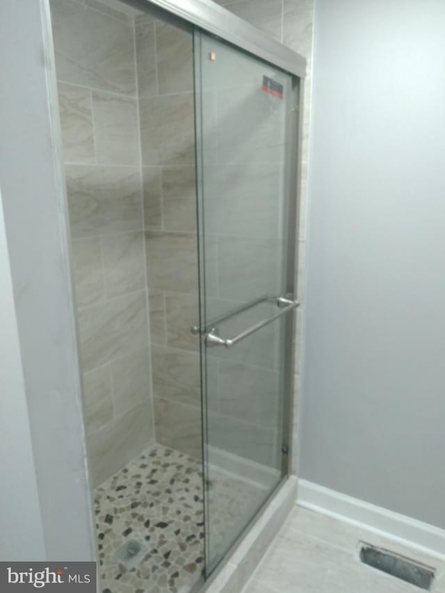 bathroom with tile flooring and a shower with door