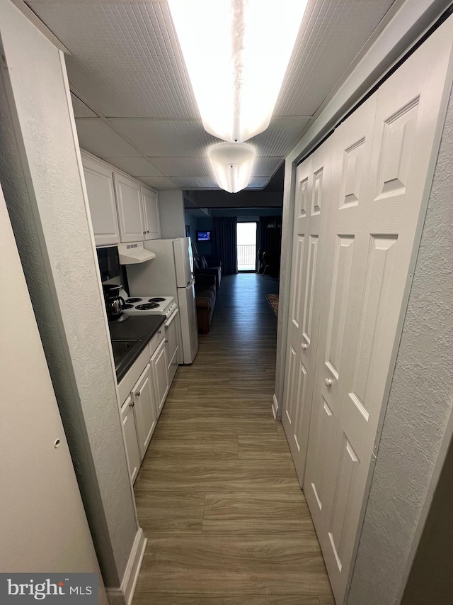 interior space with range hood, white fridge, light wood-type flooring, and white cabinetry