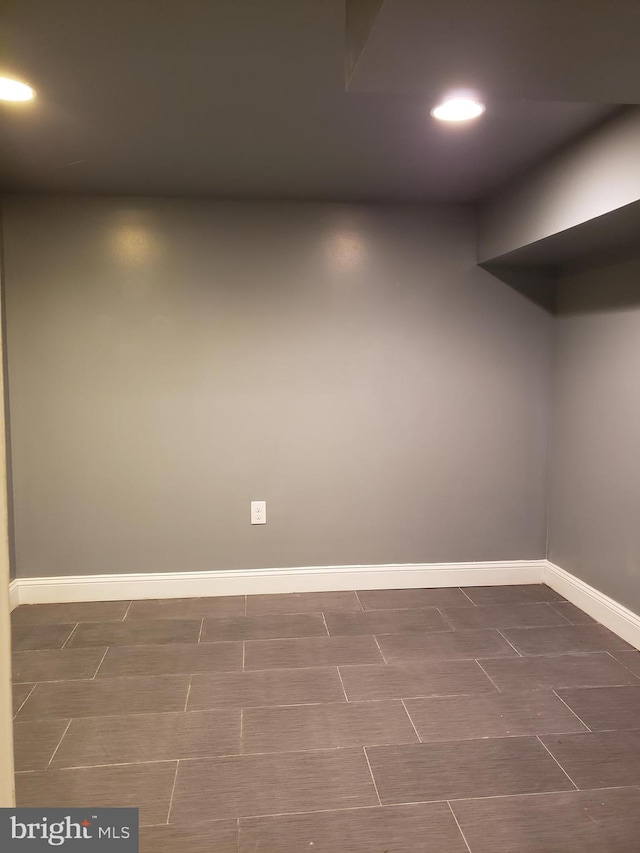 unfurnished room featuring dark tile flooring