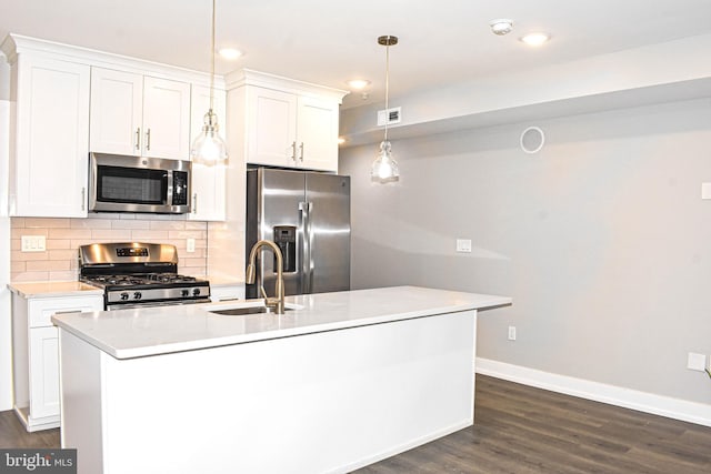 kitchen featuring dark hardwood / wood-style flooring, decorative light fixtures, appliances with stainless steel finishes, a center island with sink, and white cabinetry