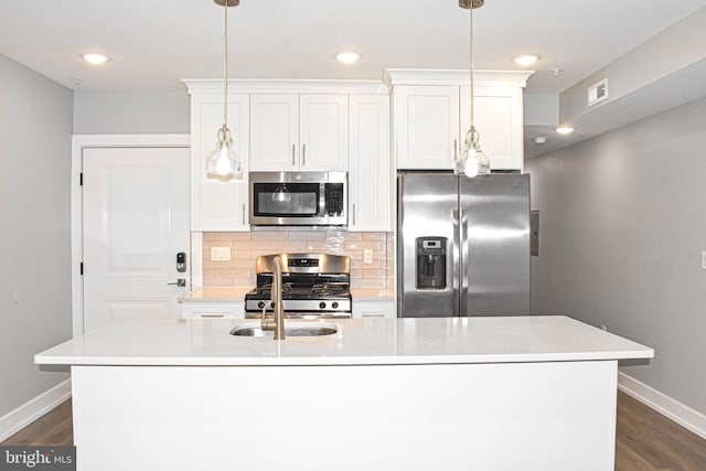 kitchen with appliances with stainless steel finishes, hanging light fixtures, dark hardwood / wood-style floors, and a kitchen island with sink