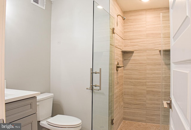 bathroom featuring toilet, a tile shower, and vanity