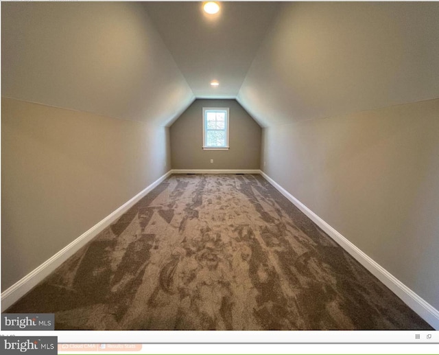 additional living space featuring lofted ceiling and dark colored carpet