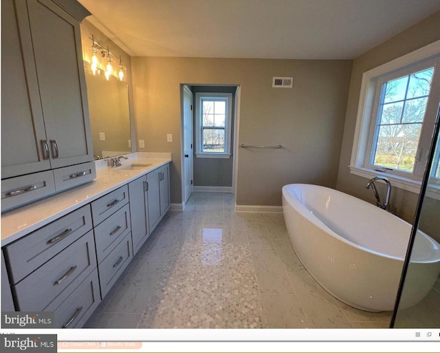 bathroom with tile flooring, a washtub, and dual bowl vanity