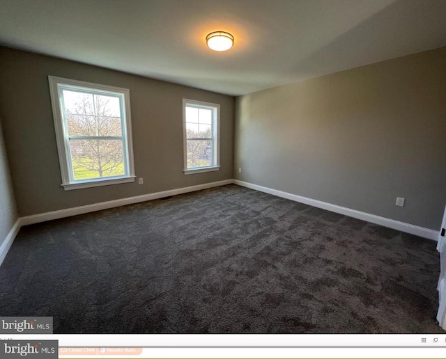 unfurnished room featuring dark carpet