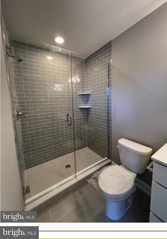 bathroom featuring walk in shower, tile floors, toilet, and vanity