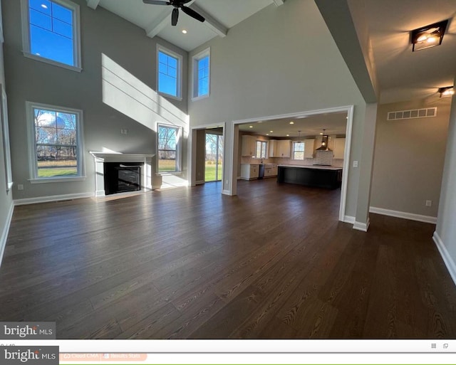 unfurnished living room with a healthy amount of sunlight, ceiling fan, and dark hardwood / wood-style flooring