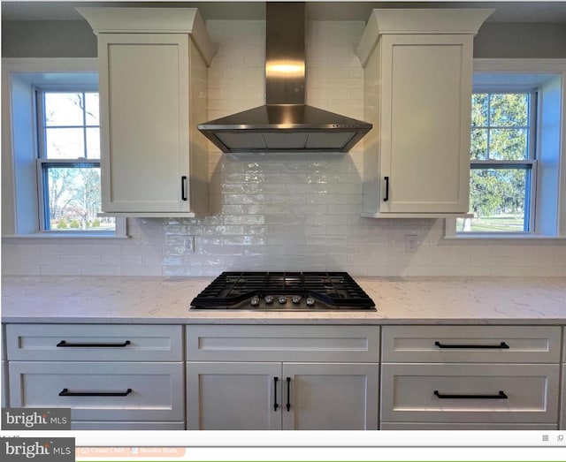 kitchen featuring backsplash, white cabinetry, and wall chimney range hood