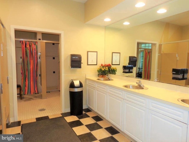 bathroom with double sink vanity, tile flooring, and walk in shower