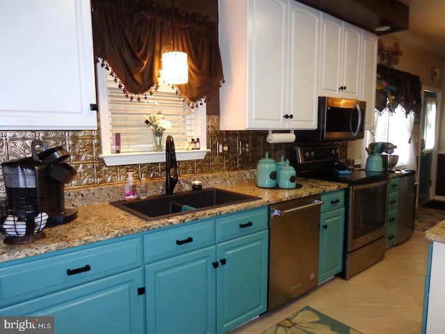 kitchen with stainless steel appliances, light stone countertops, tasteful backsplash, white cabinetry, and sink