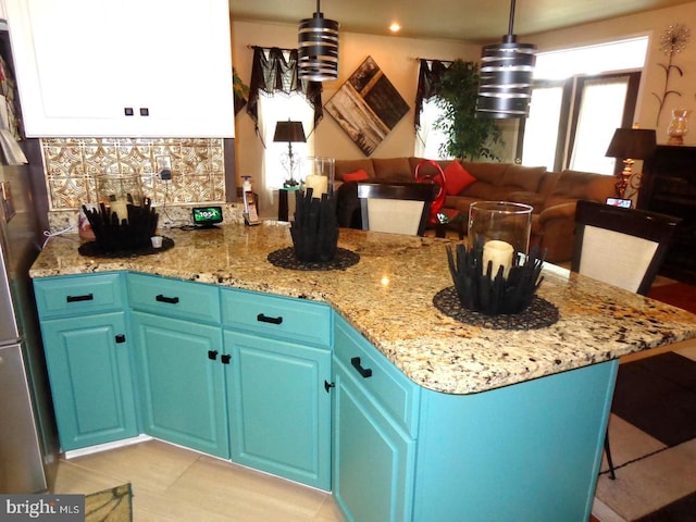 kitchen featuring a kitchen breakfast bar, light stone countertops, blue cabinets, and pendant lighting