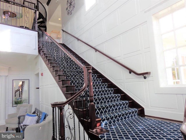 staircase with carpet, ornamental molding, and a high ceiling