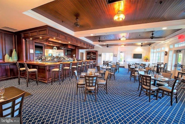 carpeted dining space featuring a tray ceiling, ornamental molding, ceiling fan, and wood ceiling