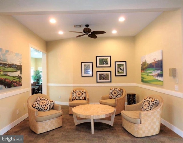 living area with dark carpet and ceiling fan