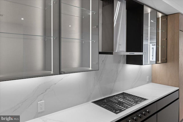 kitchen featuring decorative backsplash, black stovetop, and light stone countertops