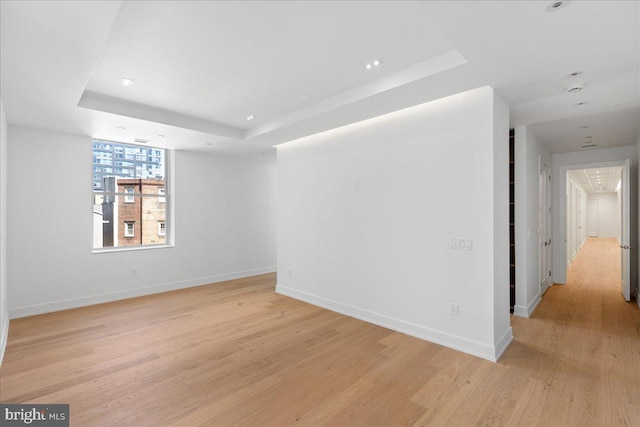 unfurnished room featuring light hardwood / wood-style flooring and a raised ceiling