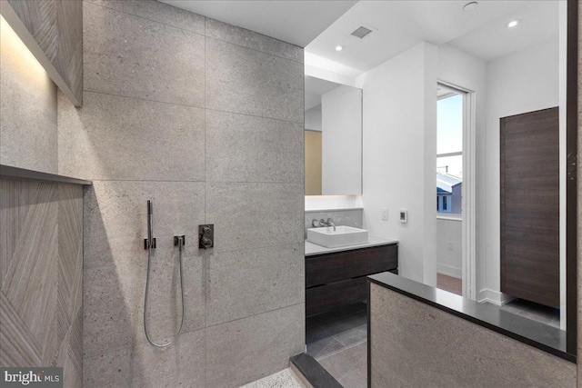 bathroom featuring a shower, vanity, and tile walls