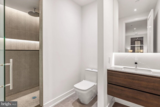 bathroom featuring tile patterned flooring, toilet, a tile shower, and vanity