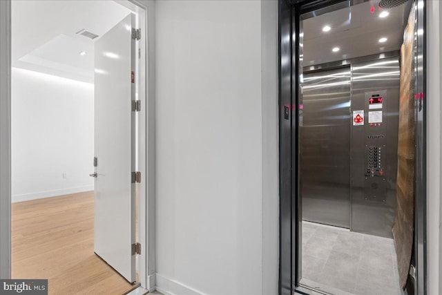 interior details featuring elevator and wood-type flooring