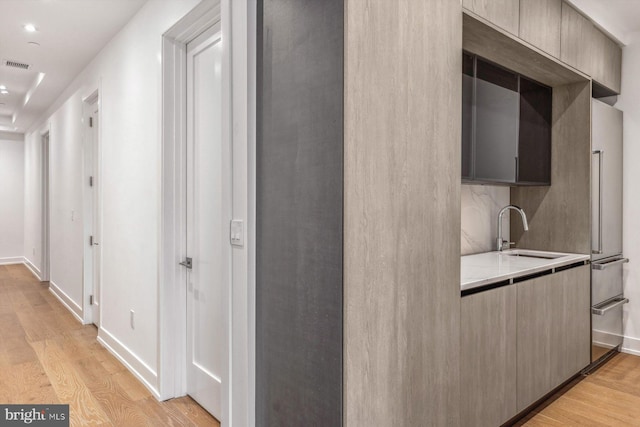 corridor featuring sink and light hardwood / wood-style flooring