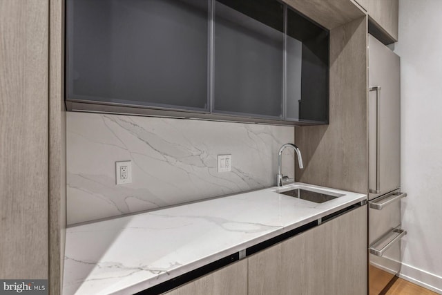 kitchen featuring light stone countertops, light wood-type flooring, and sink